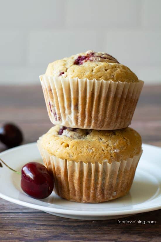 Two gluten-free cherry muffins stacked on top of each other on a plate.