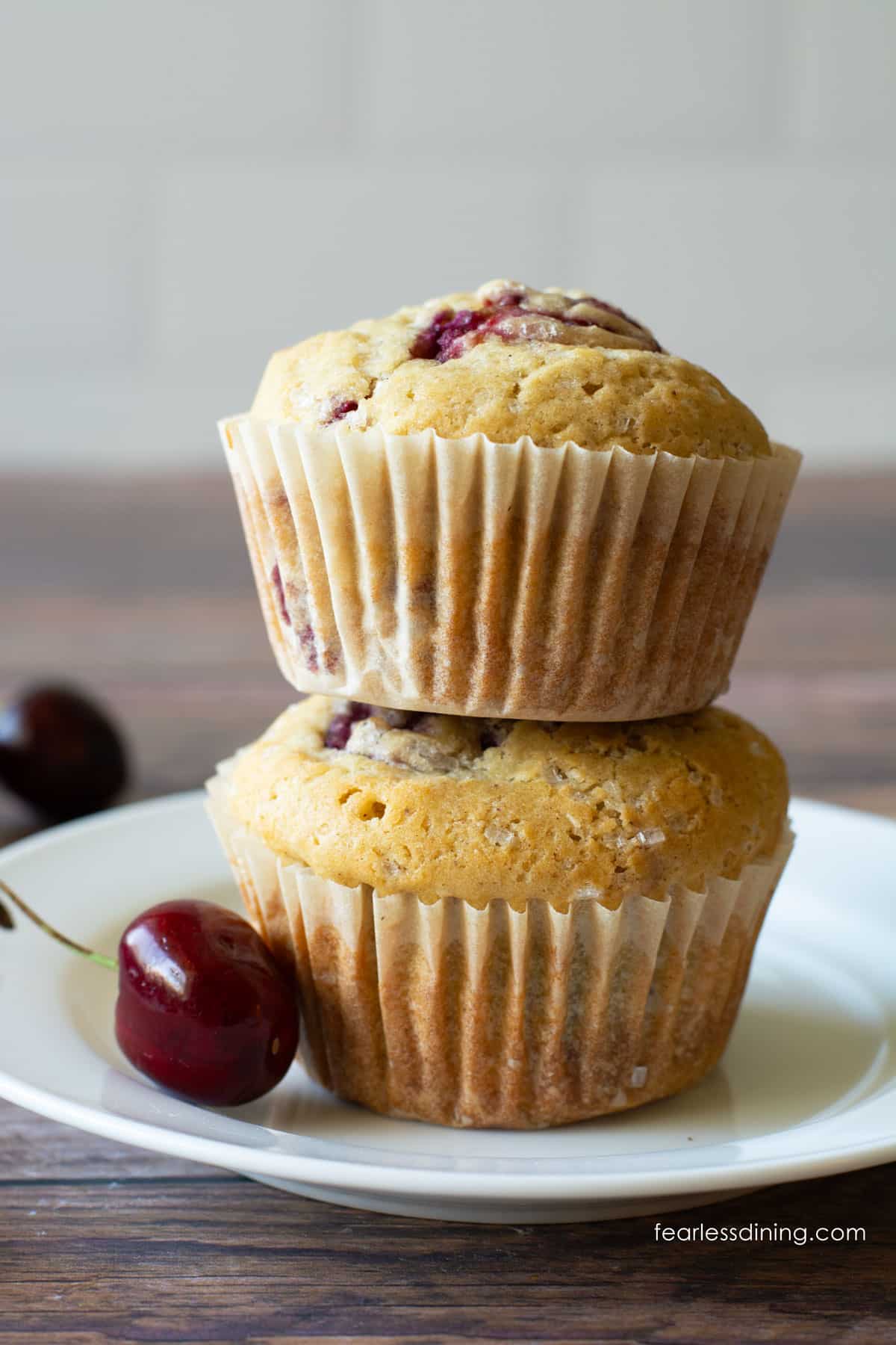 Two gluten-free cherry muffins stacked on top of each other on a plate.