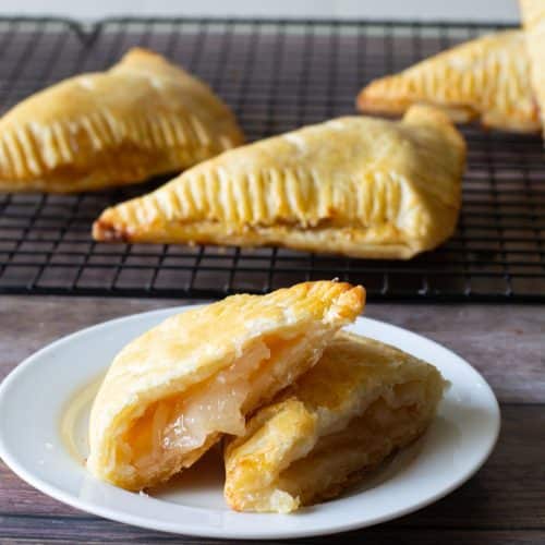 A photo of a gluten-free apple turnover on a plate. It is cut in half so you can see the flaky layers.