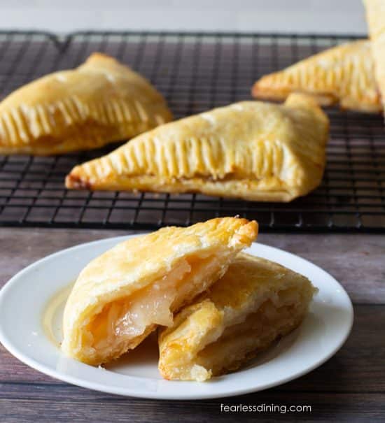 A photo of a gluten-free apple turnover on a plate. It is cut in half so you can see the flaky layers.