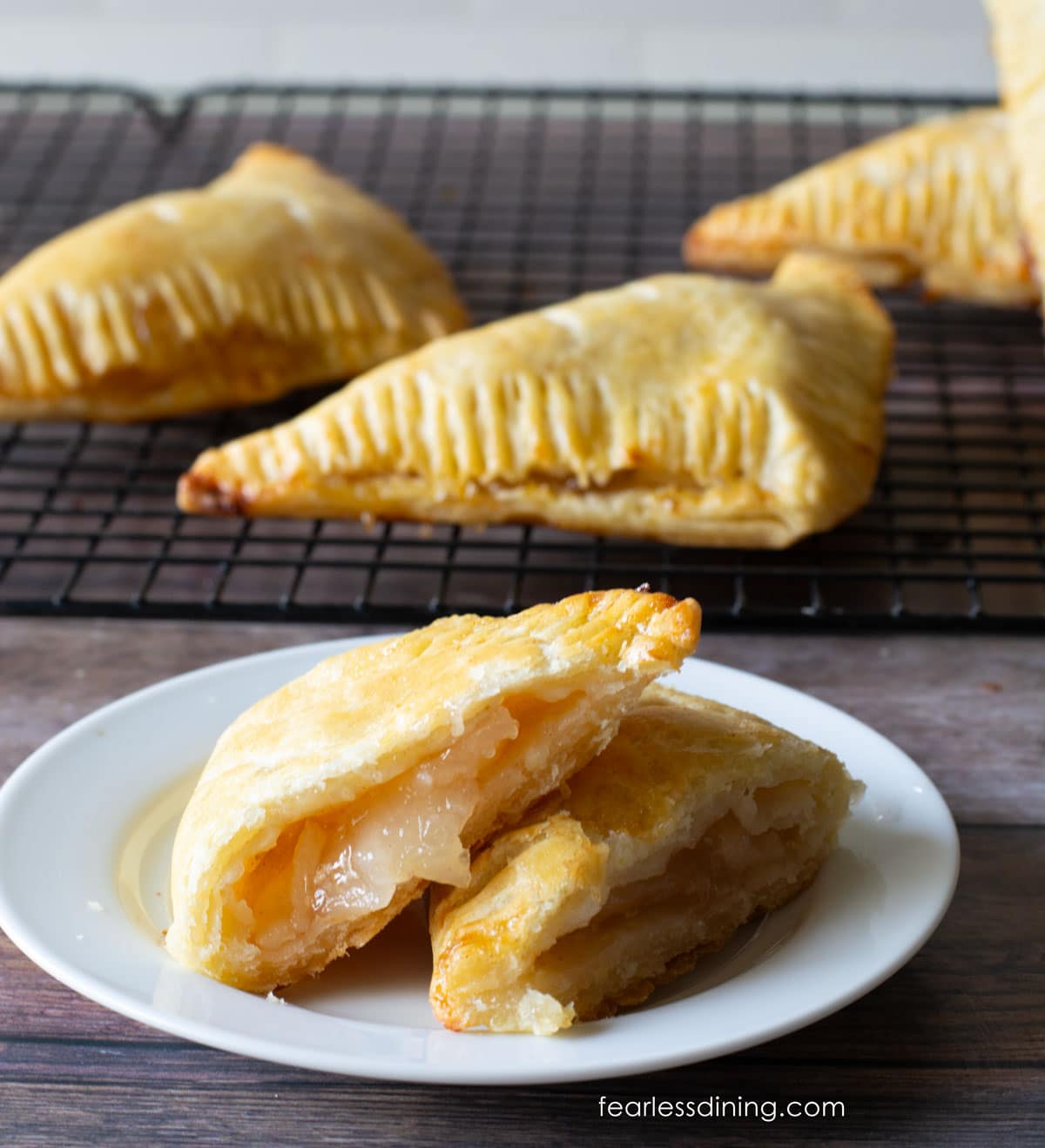 A photo of a gluten-free apple turnover on a plate. It is cut in half so you can see the flaky layers.