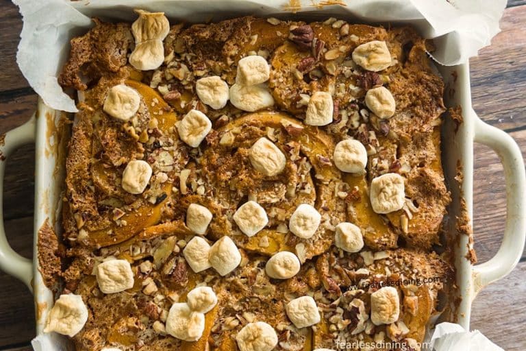 An 8x8 pan filled with baked gluten-free candied sweet potato cinnamon rolls.
