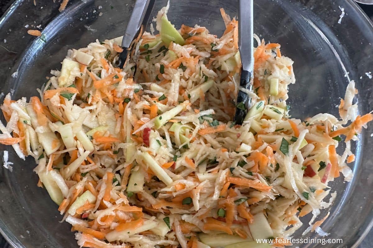 The celery root slaw tossed with the dressing in a mixing bowl.