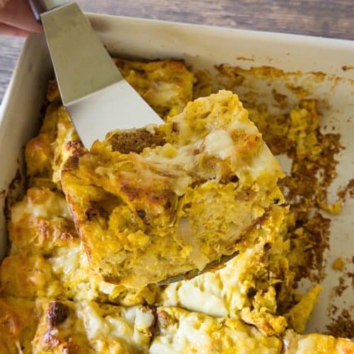 A spatula holding up a slice of the savory gluten-free pumpkin onion bread pudding.