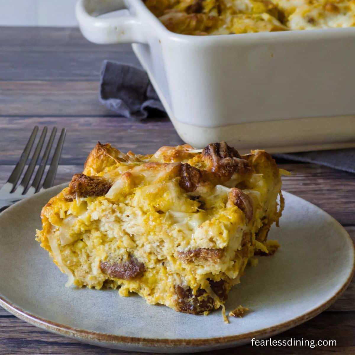 A slice of the gluten-free pumpkin and onion bread pudding on a small white plate.