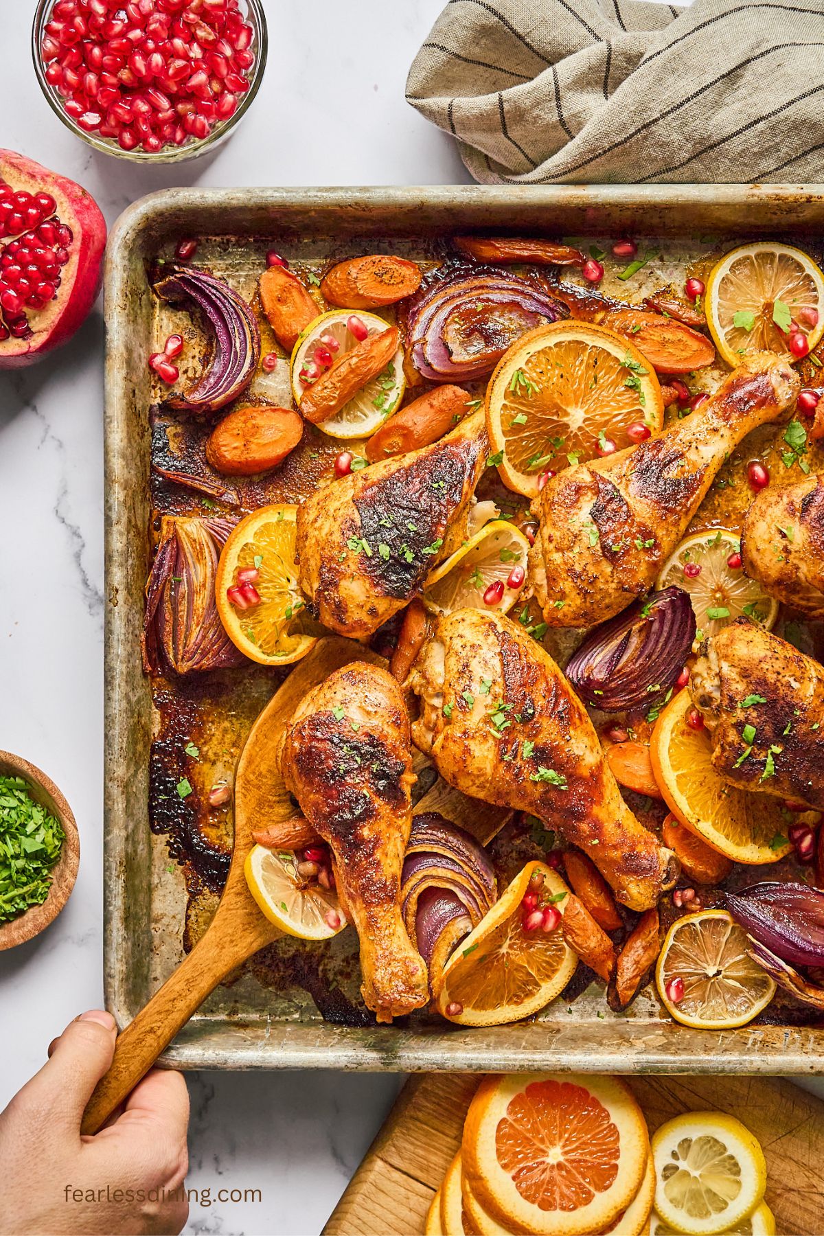 A serving spoon scooping up a baked ras el hanout chicken leg.