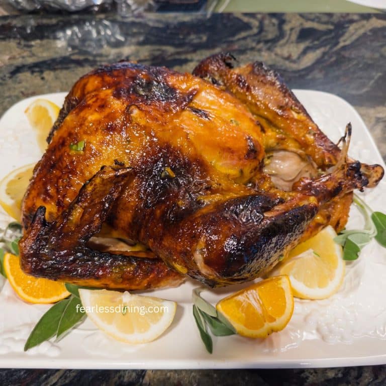 A roasted turkey with orange marmalade and sage on a platter with sliced oranges and lemons.