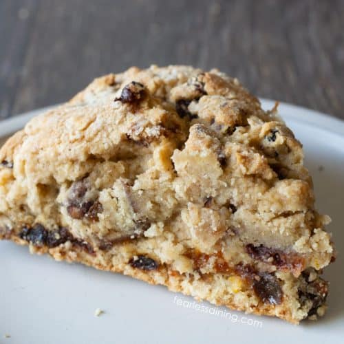 A gluten free fruit cake scone on a small white plate.