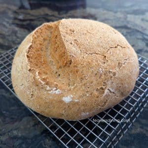 A round gluten free artisan bread boule on a cooling rack.