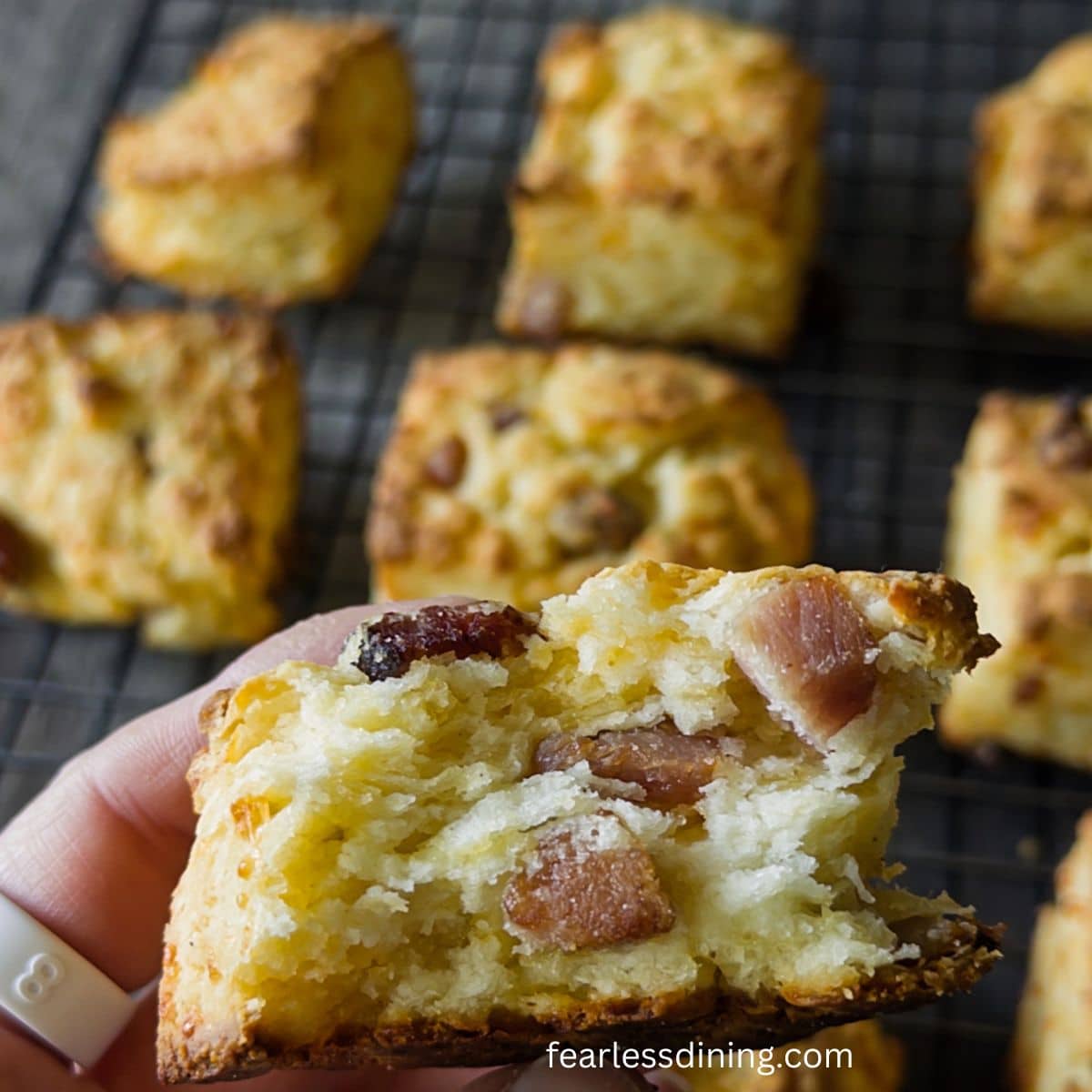 Holding up half of a bacon cheese biscuit so you can see the inside.