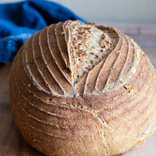 The front view of my artisan gluten free whole grain sourdough bread on a wooden cutting board.