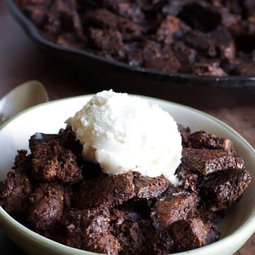 A bowl of the baked gluten free chocolate bread pudding with a scoop of vanilla ice cream on top.