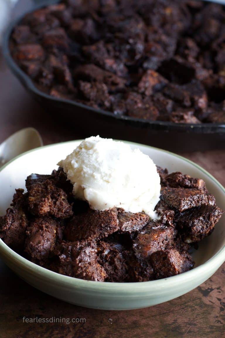 A bowl of the baked gluten free chocolate bread pudding with a scoop of vanilla ice cream on top.