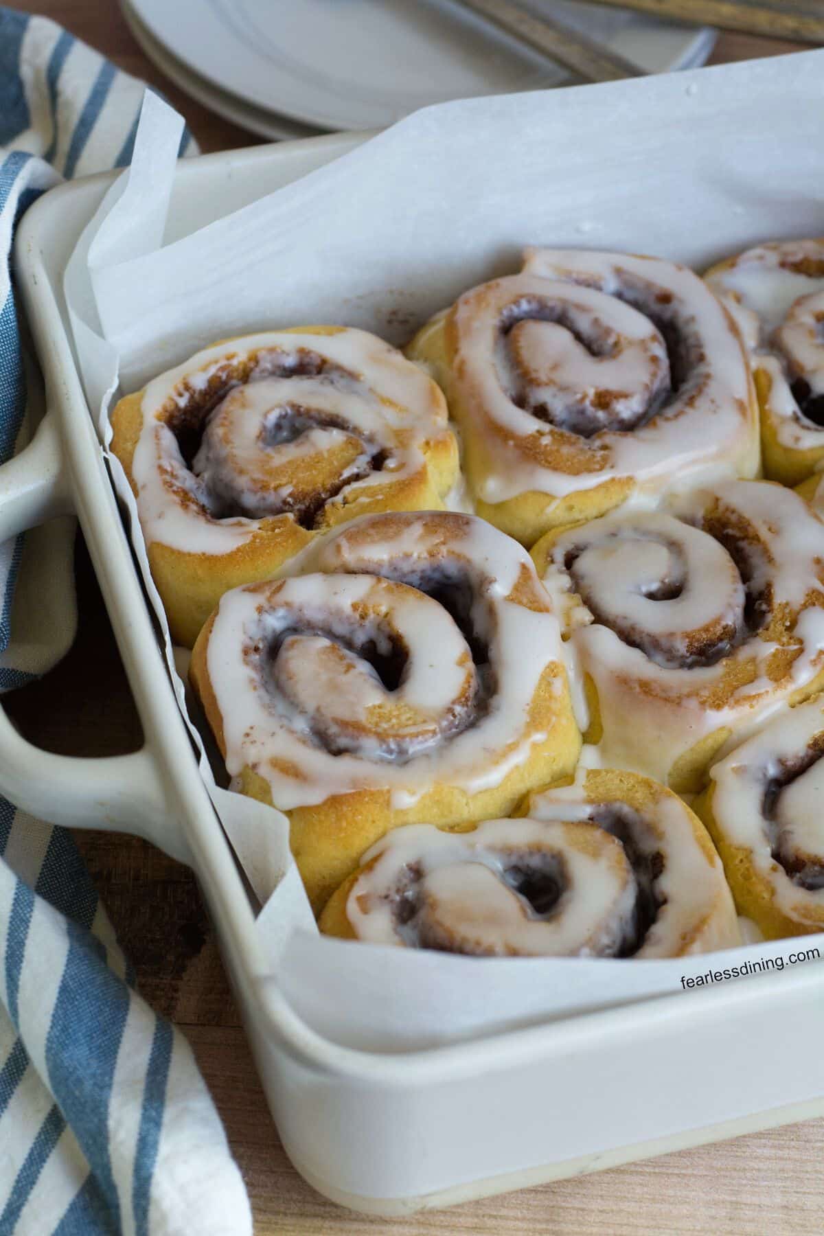 A baking dish filled with iced gluten free sourdough cinnamon rolls.