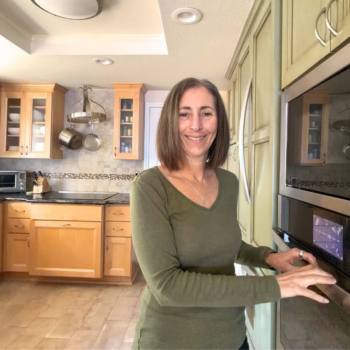 A photo of Sandi in the kitchen next to the oven.