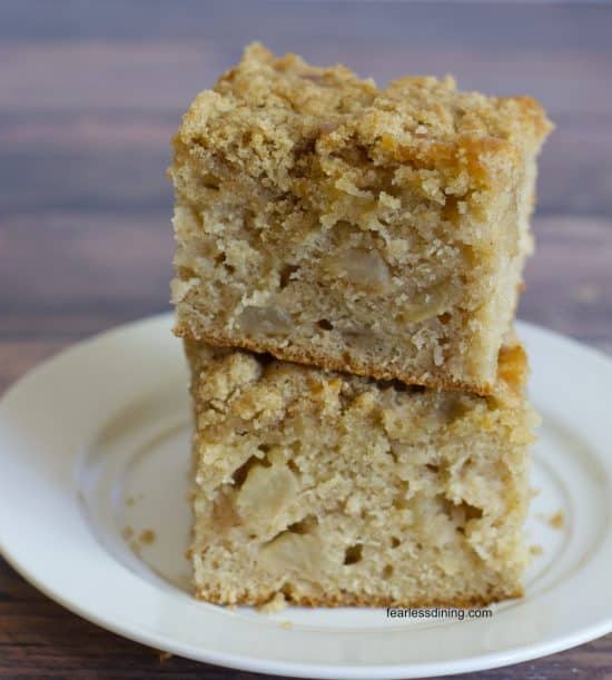A stack of two slices of gluten free apple coffee cake on a small white plate.