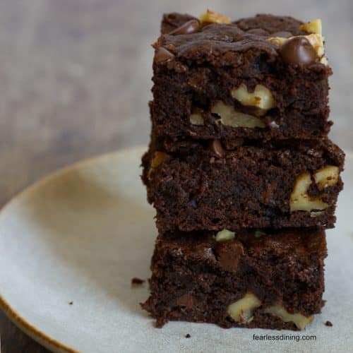 A stack of three gluten free chocolate walnut cookie bars on a plate.