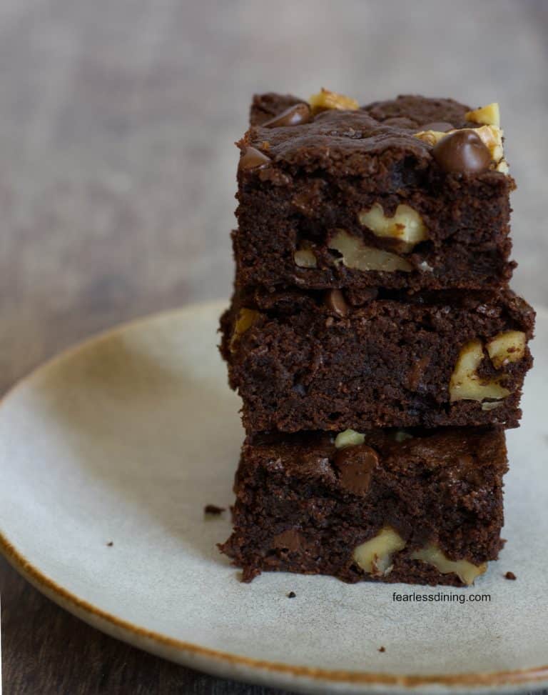 A stack of three gluten free chocolate walnut cookie bars on a plate.
