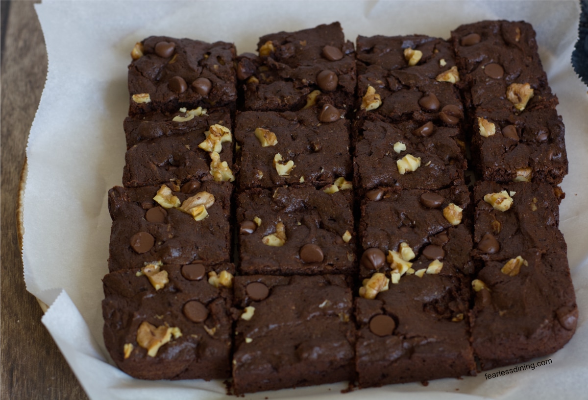 Baked chocolate walnut cookie bars on parchment paper.