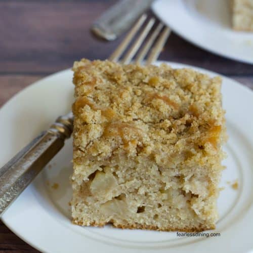 A slice of gluten free apple coffee cake on a white plate.