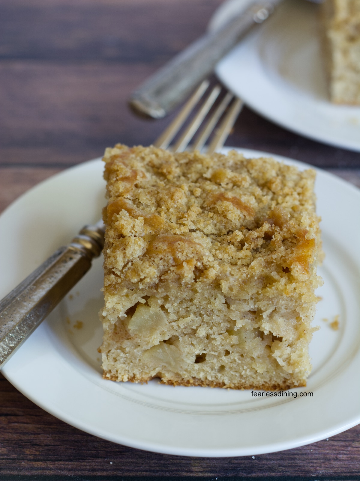 A slice of gluten free apple coffee cake on a white plate.