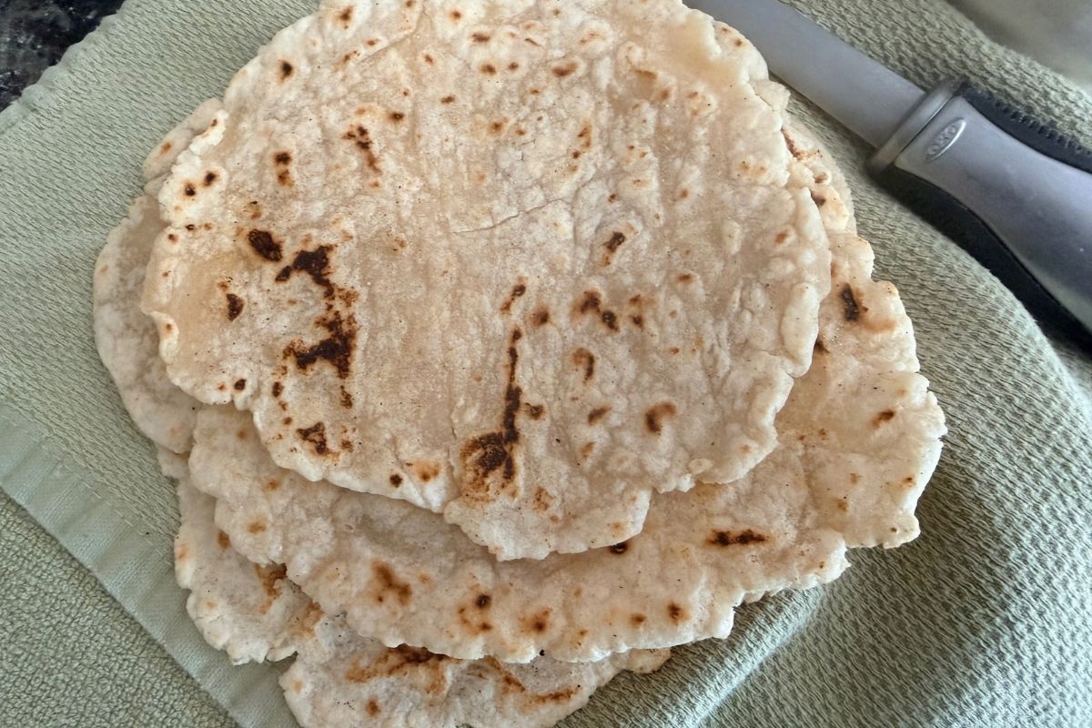 A stack of cooked flour tortillas ready to be placed into a tortilla warmer.