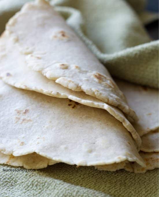 Flour tortillas on a kitchen towel folded over to show pliability.