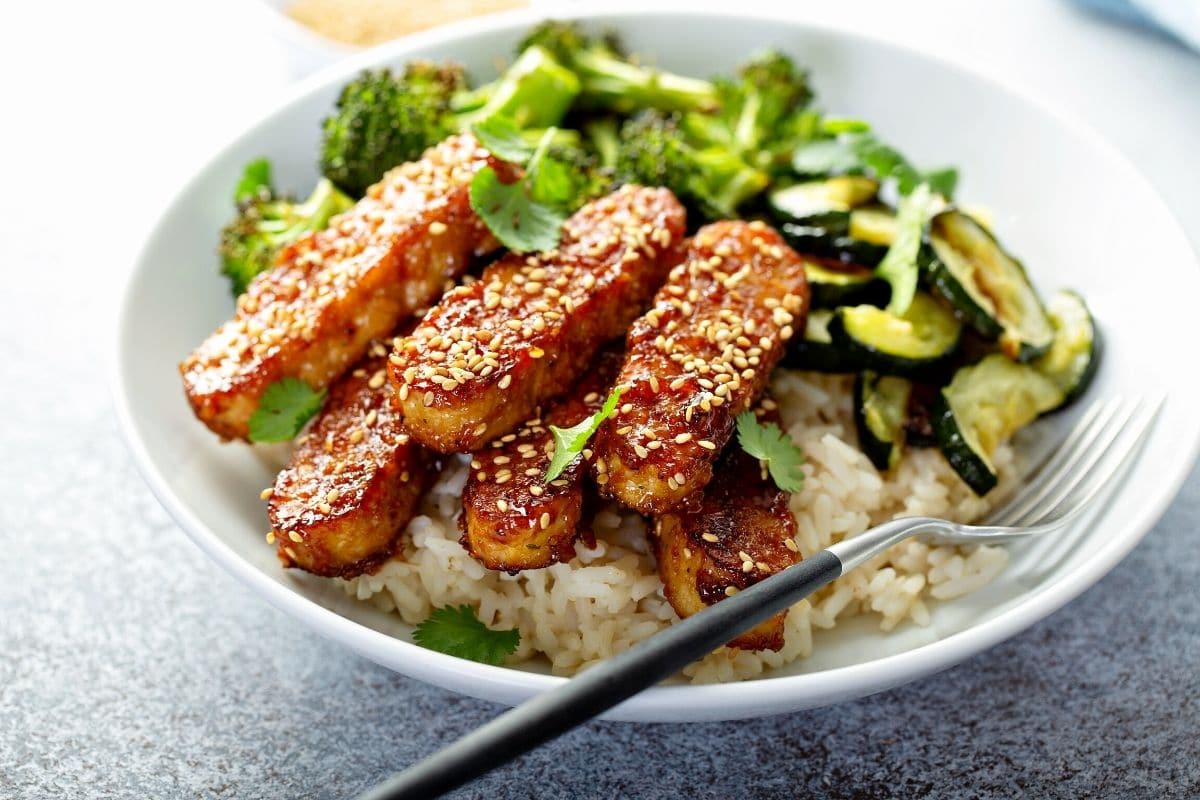 A bowl of teriyaki tempeh with rice and vegetables.