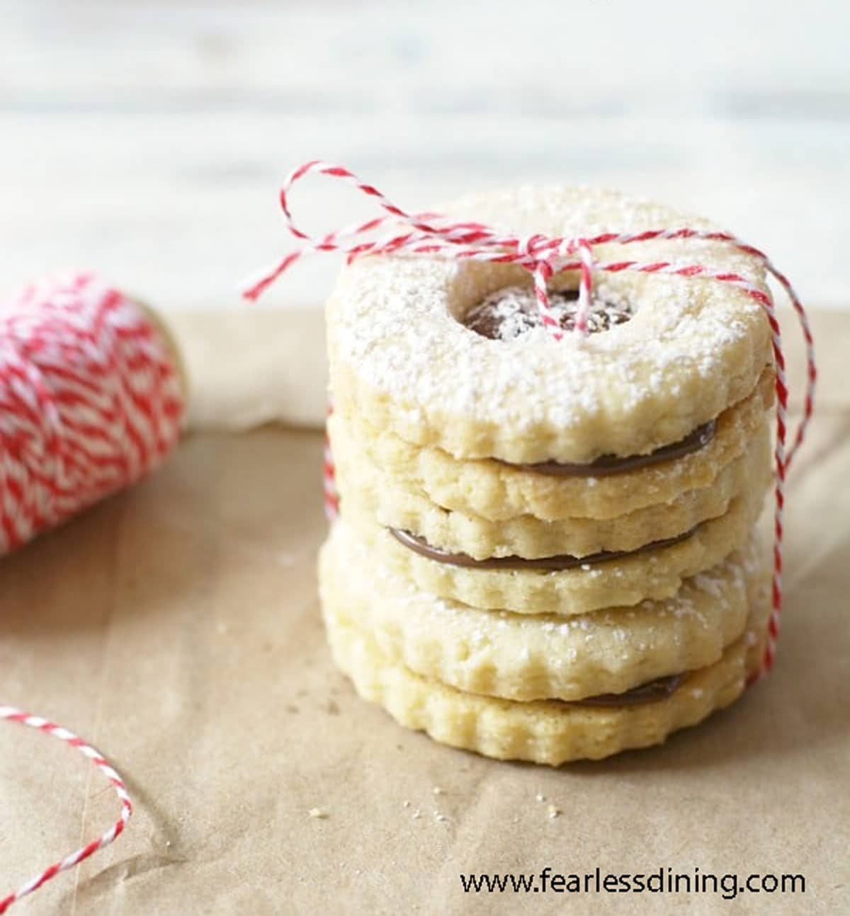 A stack of gluten free linzer cookies tied with bakers string.