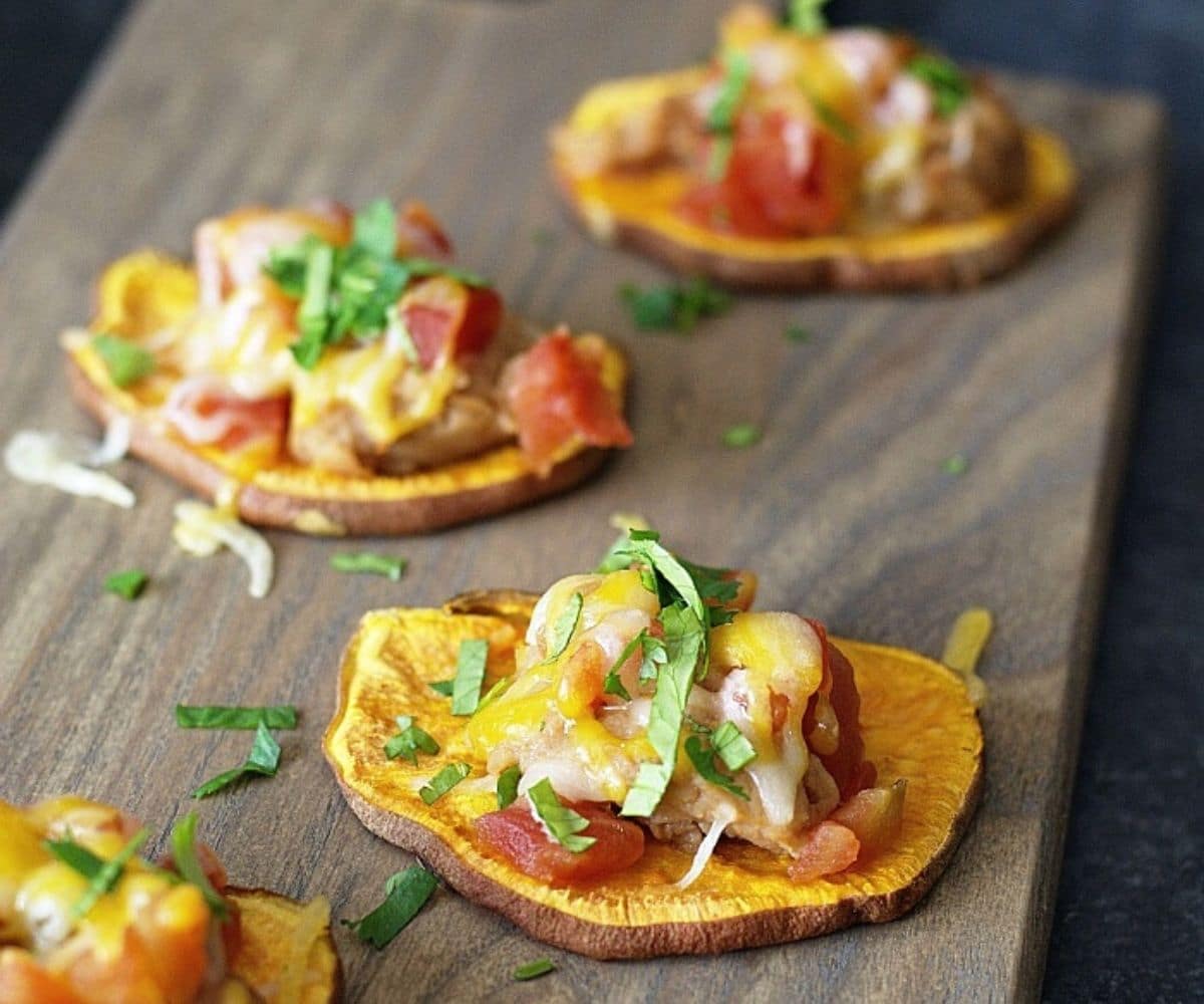 sweet potato nachos with Rotel and cheese on a wooden board.