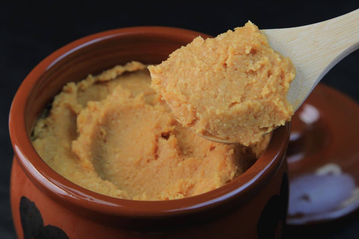 A small jar of miso paste with a spoonful.