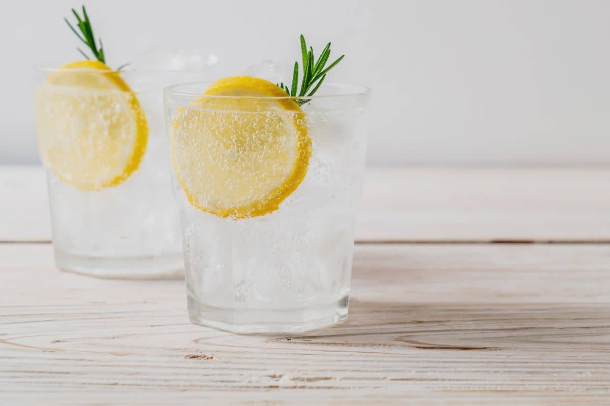 Two glasses with smirnoff ice. They are garnished with lemon and a rosemary sprig.