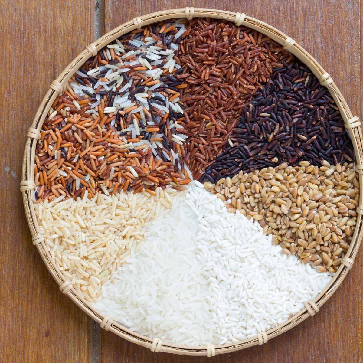 A small basket filled with different types of uncooked rice.