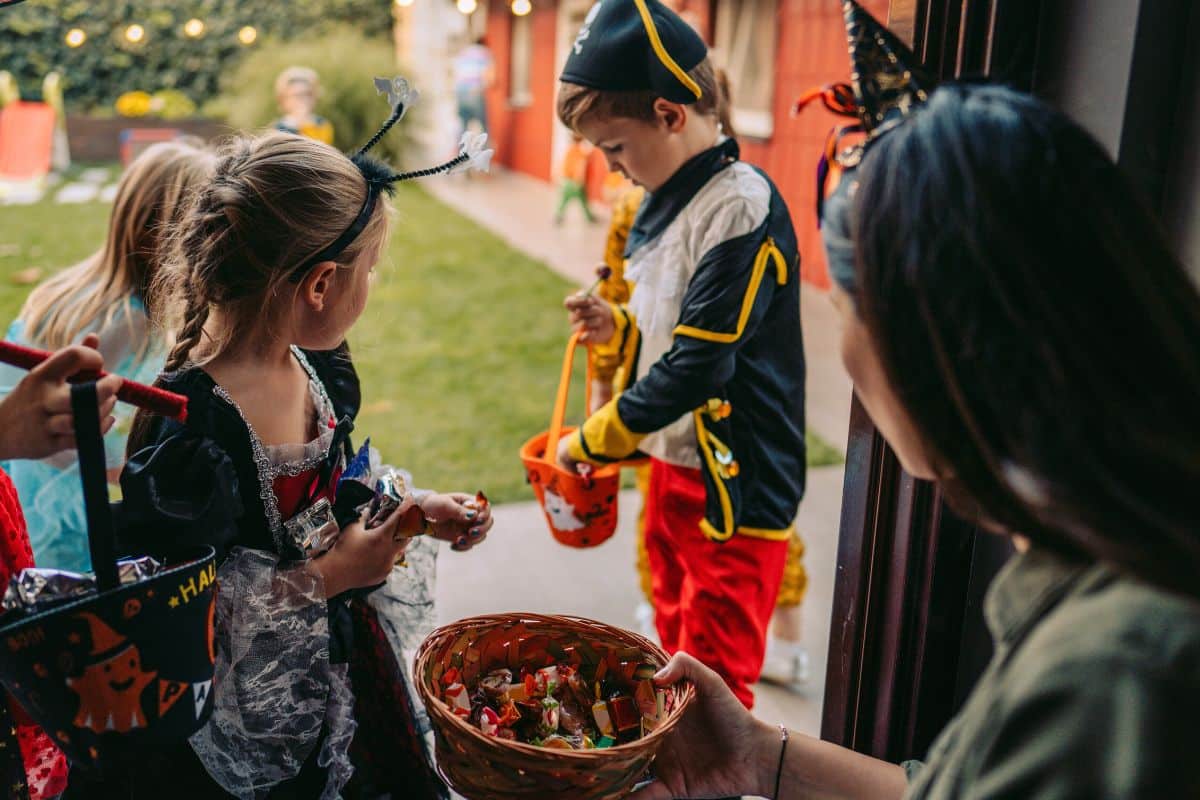 A photo of kids trick or treating getting candy.